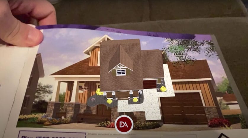 An augmented reality house model displayed over a printed home image