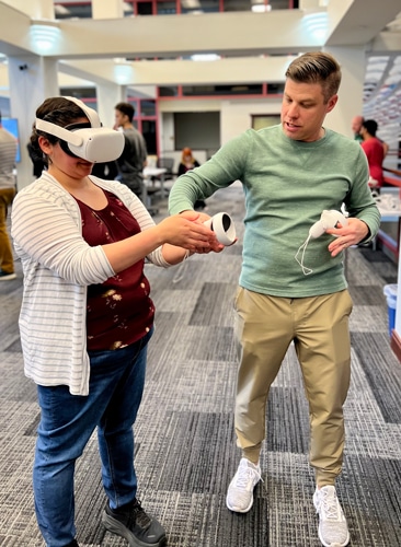 An ARS team member helping a person test a virtual reality headset and controllers