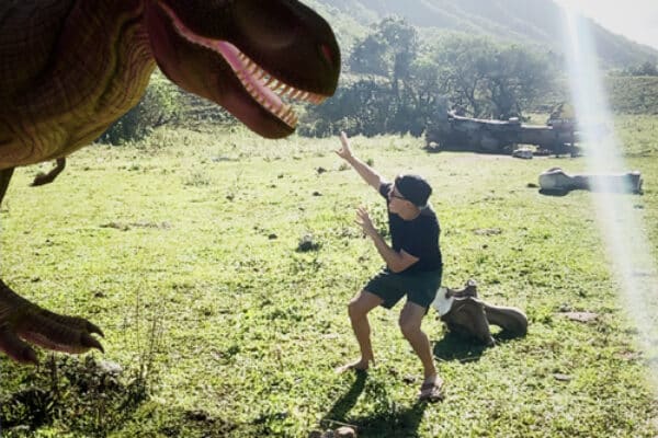 A visitor interacting with an augmented reality dinosaur at Kualoa Ranch